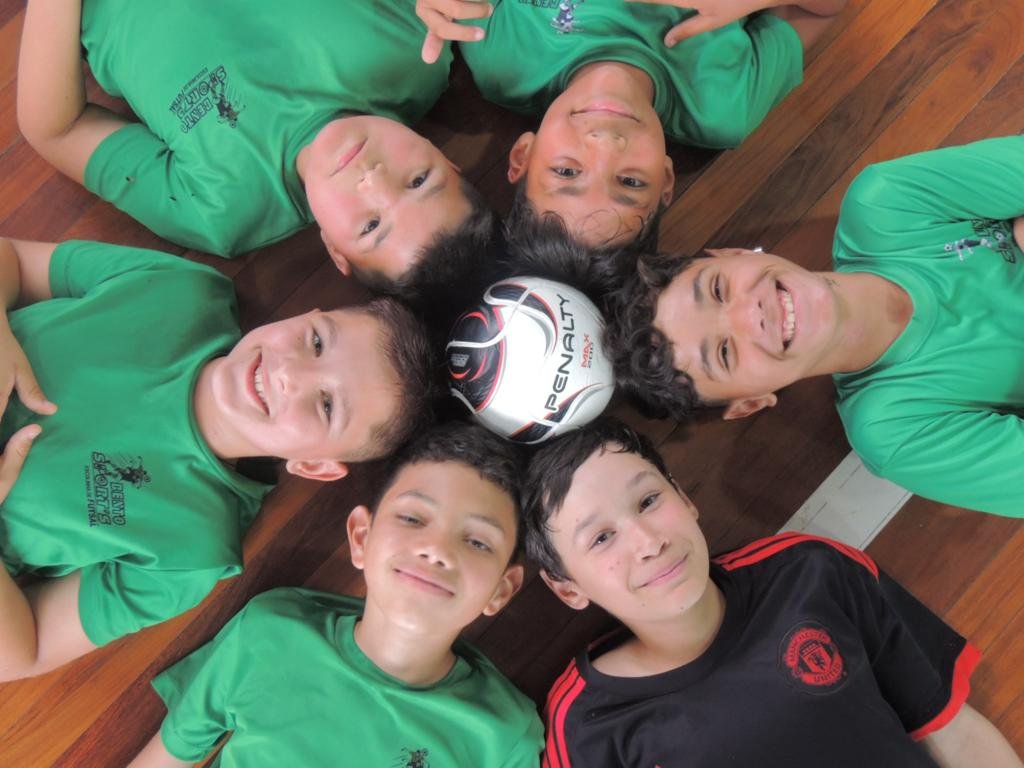 Crianças de uniforme verde com bola de futsal Penalty — projeto esportivo