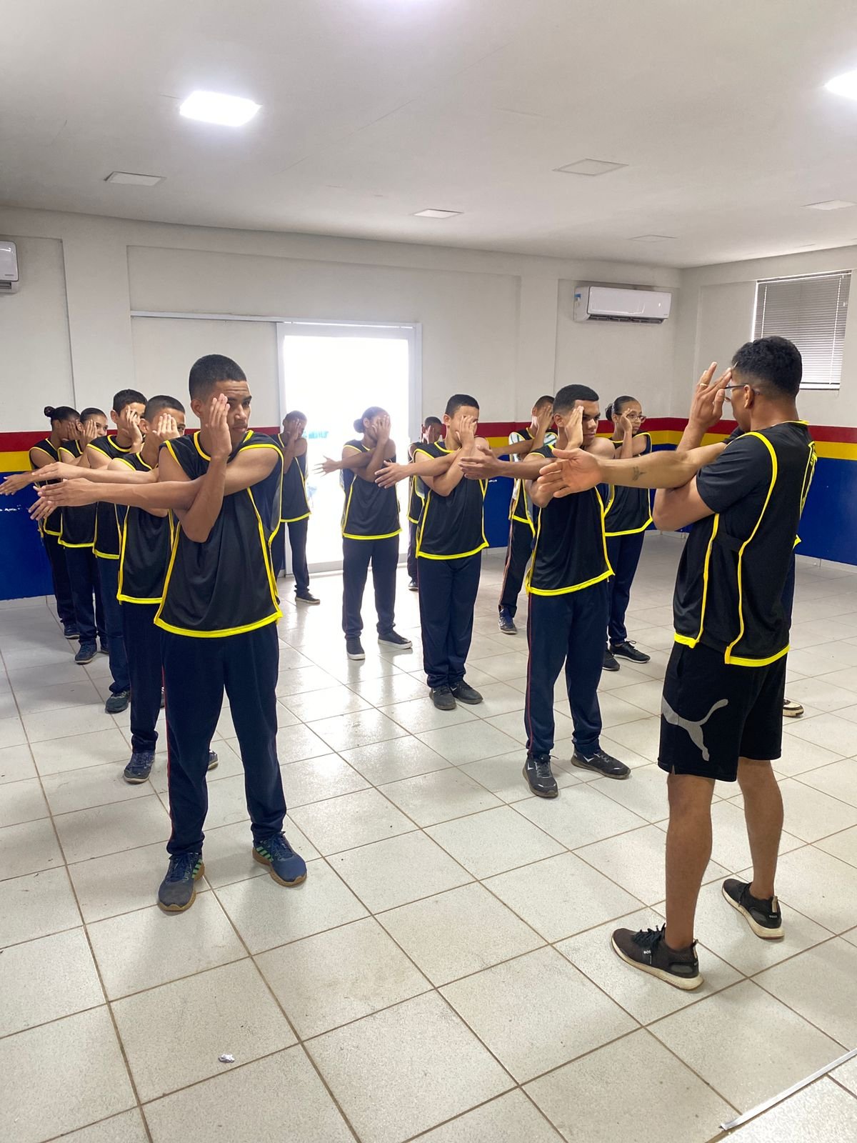 Atletas em treinamento coletivo com uniforme preto e amarelo